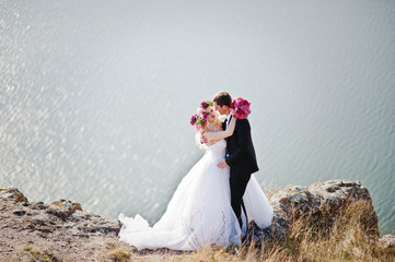 Fototapeta na wymiar Charming bride in a wreath and elegant groom on landscapes of mo