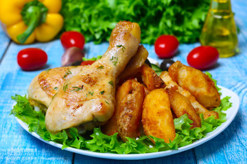 roasted chicken legs with potatoes with Greek salad on wooden background with vegetables