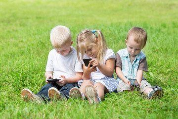 Naklejka na ściany i meble Happy kids playing on smartphones