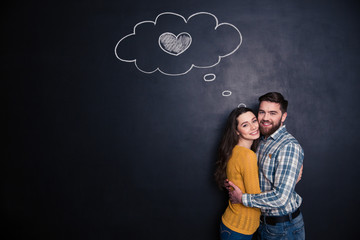 Smiling loving couple hugging over background of chalkboard