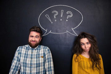 Ugly couple grimacing over chalkboard background