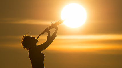 Woman playing a saxophone at the sun