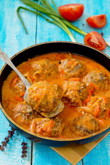 Homemade meatballs in tomato sauce and basil on a wooden table