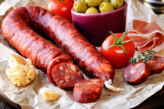 Sliced Spanish chorizo sausage with bread, olives, jamon serrano and tomatoes