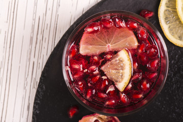Pomegranate cocktail with lemon slices over wooden background. Top view. Selective focus