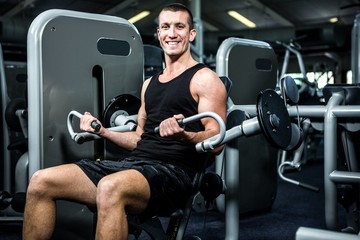 Fototapeta na wymiar Smiling muscular man using exercise machine 