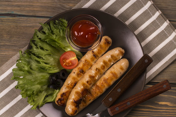 Roasted sausages with fresh vegetables over rustic background. Top view