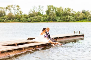 Foto op Canvas Beautiful bride and groom by a lake or river © satura_