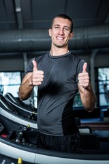 Fototapeta na wymiar Muscular man on treadmill showing thumbs up