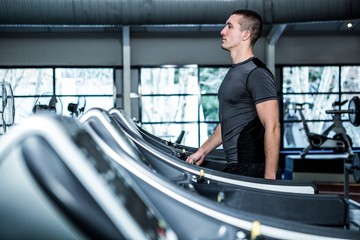 Fototapeta na wymiar Concentrated muscular man using treadmill
