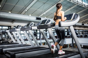 Fototapeta na wymiar Rear view of woman jogging in treadmill