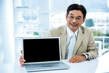 Smiling asian businessman showing his laptop