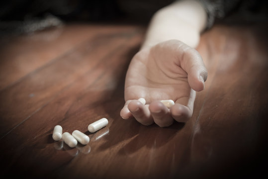 Drug abuse concept, passive hand on floor with spilled pills 