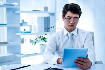 Serious asian businessman using his tablet