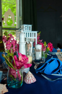 Festive table setting with starfishes, napkins, glasses and candles, bright summer table decor