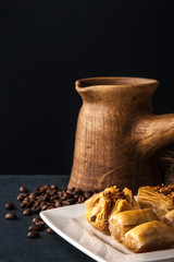 Wooden cezve with baklava on the dark table vertical