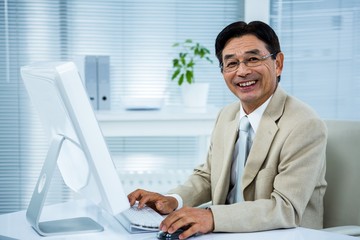 Smiling businessman using his computer