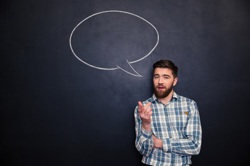 Bearded man talking over blackboard background with drawn  speech bubble