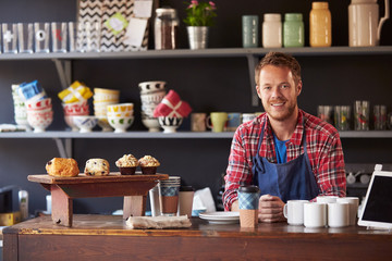 Portrait Of Male Coffee Shop Owner Standing Behind Counter