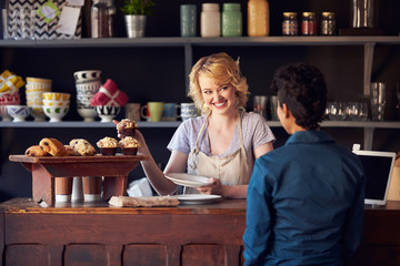 Staff Serving Customer In Busy Coffee Shop