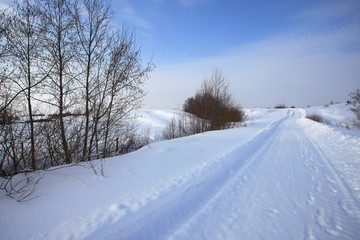Fototapeta na wymiar Winter snowy rural road and blue sky landscape
