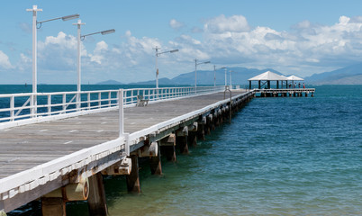 Pier on tropical island in North Queensland. A family enjoys the tranquil view.