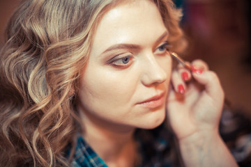 make-up artist doing professional make up of young woman