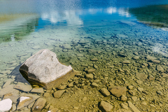 Un rocher dans une eau bleue transparente d'un lac de montagne