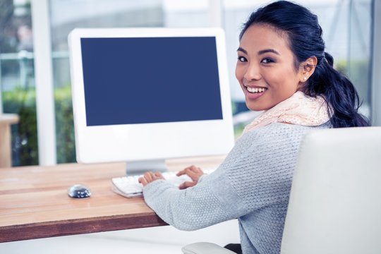 Smiling Asian Woman Using Computer Looking Back At The Camera