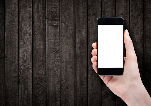 Female hand holding smart phone on wooden background