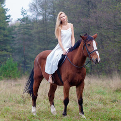Fototapeta premium romantic sensual girl in white dress on a horse in the forest