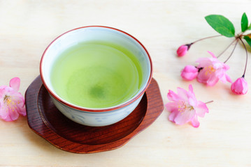 green tea with pink flowers on wooden board