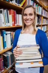 Happy female student taking books in the library