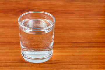 Glass of water on wooden table with space for text