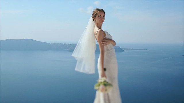 Beautiful sexy brunette bride in wedding dress with bouquet in her hands  standing at the roof and smiling