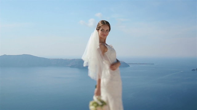 Beautiful sexy brunette bride in wedding dress with bouquet in her hands looks back and smiling