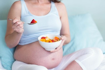 Obraz na płótnie Canvas Pregnant woman eating fruit