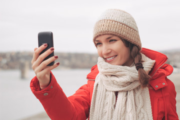 Young woman using smart phone outdoors in winter