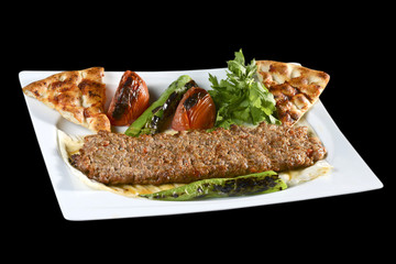 Adana kebab is a long, hand-minced meat kebab mounted on a wide iron skewer and grilled on an open mangal filled with burning charcoal.