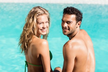 Fototapeta premium Rear view of couple sitting by the pool