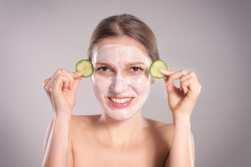 Obraz na płótnie Canvas Beautiful young woman receiving facial mask of cucumber