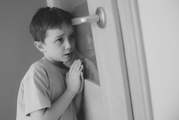 Little sad boy overhears fight of his parents - B&W