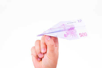 A hand holding a paper plane made with a 500 euro note on white background