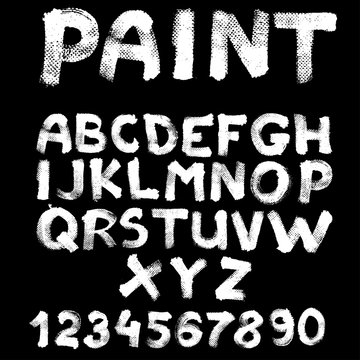 Hand-drawn font on textured paper with paint strokes on black ba