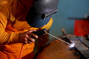 Close-up worker with protective mask welding metal.