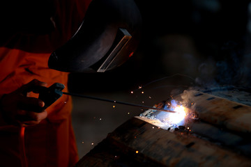 Close-up worker with protective mask welding metal.