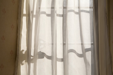 Window Shadows. Sunshine makes interesting shadows on the net curtains that are part of dated decorations of a retro interior.