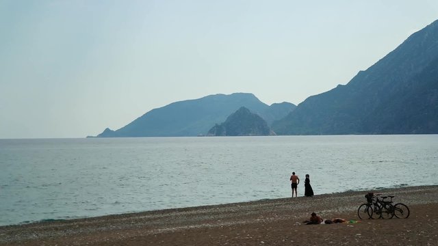 Young couple swim and talk on the beach (time lapse)