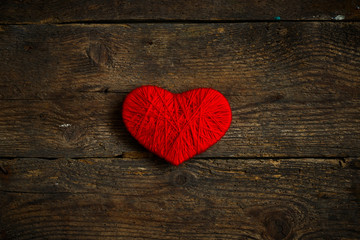 Red heart shape made from wool on old shabby wooden background