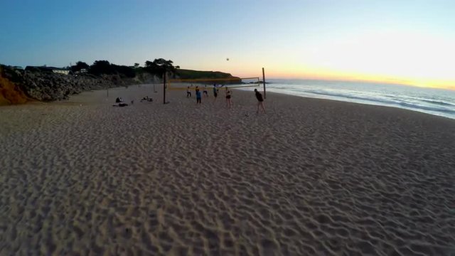 This video is about 4k Beach Volleyball Aerial Flying Overhead Ocean Sunset Group Athletic Wide Tracking Sand Sports